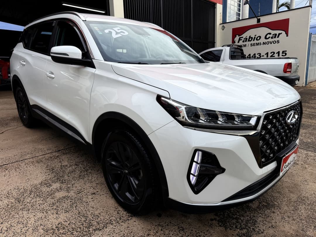 Chery Tiggo 7 branco no pátio da Fábio Car, com a placa vermelha da loja ao fundo