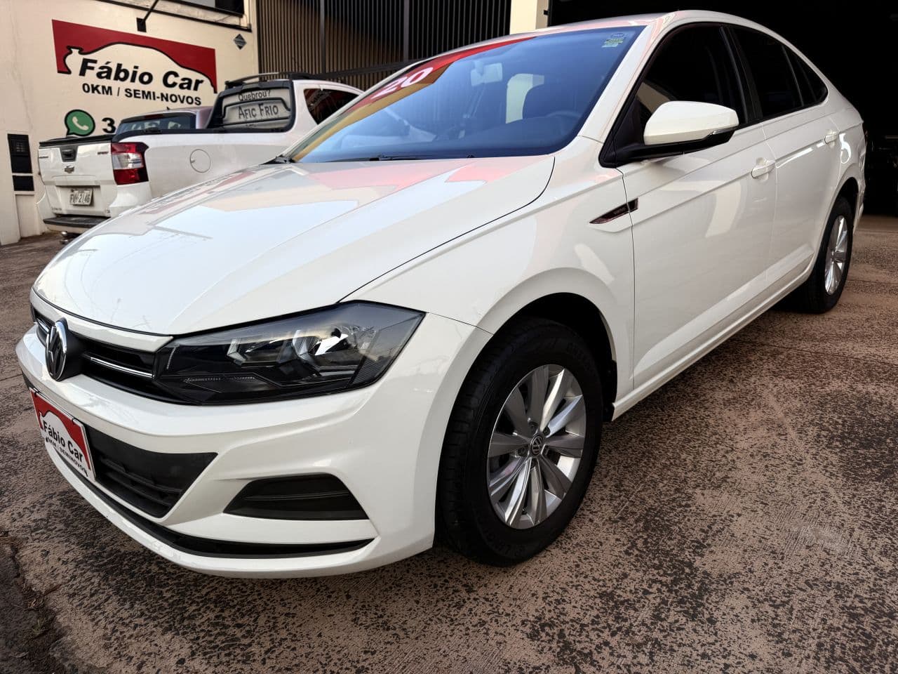 Pátio da Fábio Car com o letreiro vermelho da loja e o WhatsApp na parede
